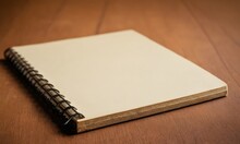 A Spiral Notebook, A Type Of Publication, Rests On A Rectangular Wooden Table, A Common Office Supply Often Made From Hardwood Flooring. The Notebook Is Bound With Metal Ring Binder