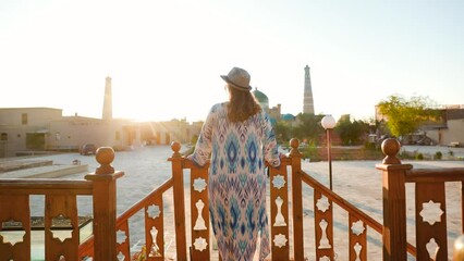 Wall Mural - Tourist woman in ethnic dress near mosque in Ichan Kala of Khiva