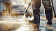 a man washes the sidewalk and curb in the city with a high pressure washer in the sun early in the morning
