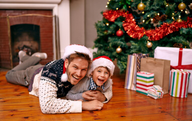 Wall Mural - Father, son and happy with portrait on christmas for celebration, playing and love on floor with santa hats. Family, man and child with smile, relax and enjoying holiday season in living room of home