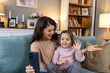 © Graphicroyalty - Happy mother and kid daughter waving hands at phone camera for video call, smiling mom and child girl having fun greeting online by phone making videocall via application with grandparents.