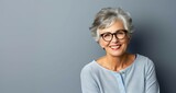 Fototapeta  - Mujer mayor sonriente con gafas fondo gris azul