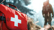 Close-up of a red first aid kit outdoors with a hiker in the background, symbolizing emergency preparedness in nature.