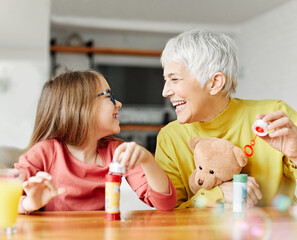 Wall Mural - child grandparent granddaughter grandmother bubble soap blowing fun together girl grandchild family senior smiling woman female happy adult lifestyle generation childhood togetherness