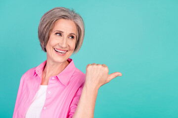 Poster - Photo of cheerful mature aged white hair business woman direct thumb empty space curious discounts isolated on cyan color background