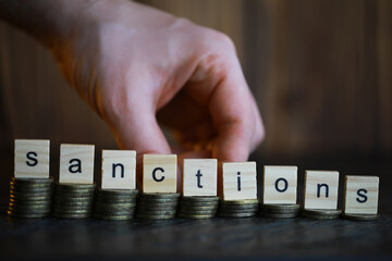 Poster - Word Sanctions made of wooden block letters with coins stacks