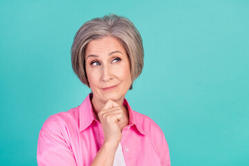 Poster - Portrait of retired business woman in pink shirt touch chin looking empty space when brainstorming isolated on blue color background