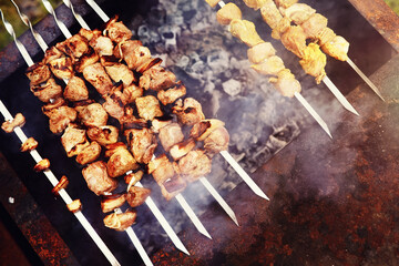 Wall Mural - Selective focus. Cooking barbecue on the mangal in nature. Grilled tasty meet cooking on the party. Traditional Russian shashlik on a barbecue skewer on sunny forest.