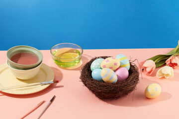 Colorful background with Easter eggs on nest, brushes and flowers decorated. At Easter, people often give each other colorful decorated eggs