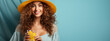 A radiant woman with a sunny hat and curly hair smiles as she enjoys a fresh orange juice, embodying a joyful summer vibe