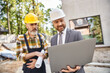© LIGHTFIELD STUDIOS - focus on laptop in hands of blurred architect and builder in safety helmets on construction site