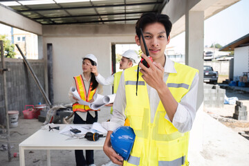 Wall Mural - Portrait of a male engineer at a construction site using a walkie-talkie. Standing in charge of planning a construction project in formal attire, wearing a hard hat, a successful civil engineer.