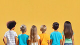 Fototapeta Psy - Group multiracial funny children. Yellow pastel background. Dressed in colorful T-shirts and jeans.International Children Day.Copy space.Rear view.