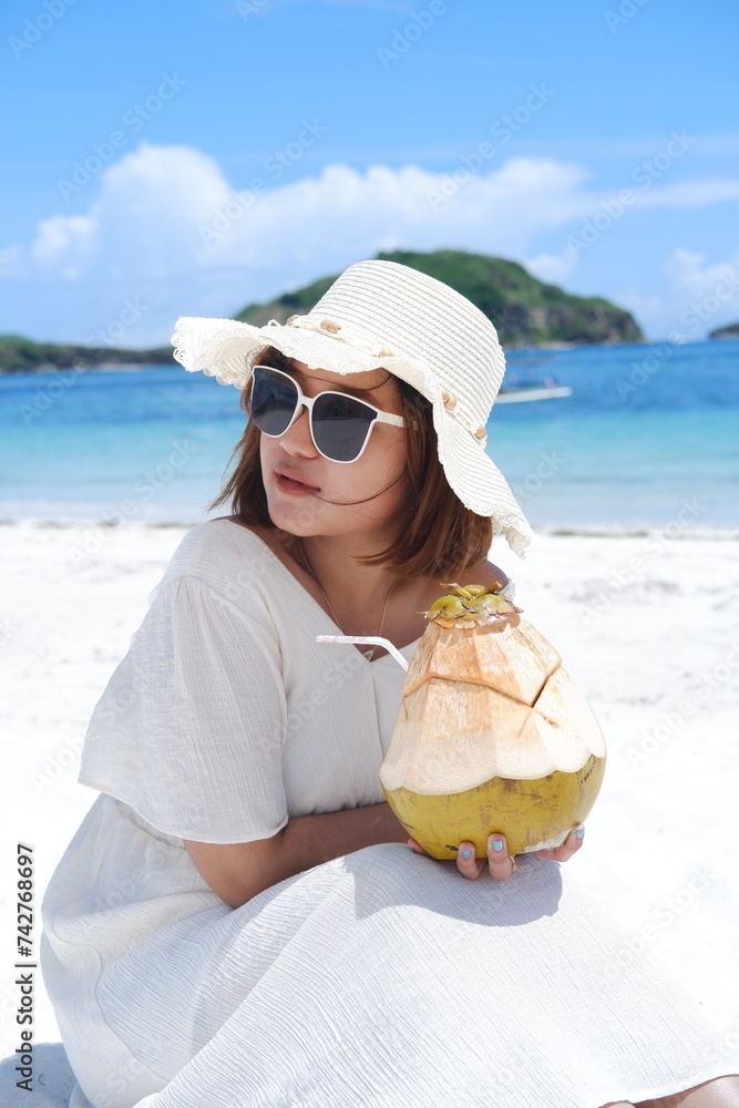 an Asian girl in a cute beach dress is on holiday at the beach while ...