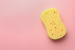 New yellow sponge on pink background, top view. Space for text