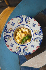 Wall Mural - Italian pasta with cheese sauce and basil in a vintage plate.