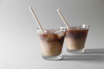 Wall Mural - Refreshing iced coffee with milk in glasses on grey background. Space for text