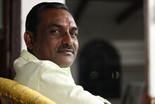 An Indian Man With Mustache Wearing  Green Formal Shirt With Bokeh Dark Background Looking Backwards