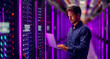 © Dzenka - Data center manager looking at laptop in server room. Ai generated.