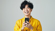 © EmmaStock - Asian Young 30s wearing yellow shirt holding mobile phone on the isolated gray background cheerful