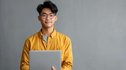 asian young content creator wearing yellow shirt holding laptop on the on isolated gray background c