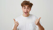 An ecstatic young man in a white shirt pointing at himself with both hands, his expression one of joyful surprise.