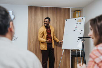 Wall Mural - A cheerful African American man engages colleagues during a presentation in a modern office setting.