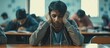 © vxnaghiyev - Indian man student and bored in classroom tired and stress with notes examination or task Young male guy or exhausted for education test or notes for assignment with headache and depressed