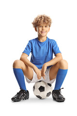 Wall Mural - Happy boy in a sport jersey sitting on a football