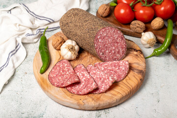 Wall Mural - Peppered salami and slices on cutting board. Italian salami with pepper on gray background