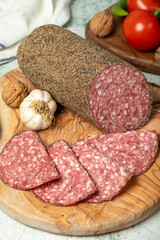 Wall Mural - Peppered salami and slices on cutting board. Italian salami with pepper on gray background