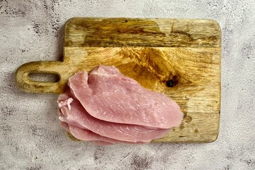 On a gray background on a wooden board there are 4 pieces of raw turkey meat steak. view from above . kitchen . low-calorie meat. copy space. cooking