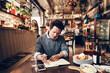 © Davor - Focused male restaurant owner managing business finances and inventory in cozy bistro