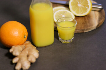 Wall Mural - Top view of homemade orange, lemon and ginger drink in a glass bottle with a small shot glass