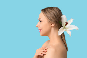 Poster - Beautiful young woman with lily flower on blue background