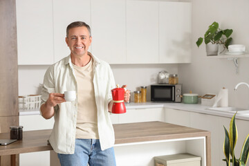 Poster - Mature man with geyser coffee maker and cup in kitchen