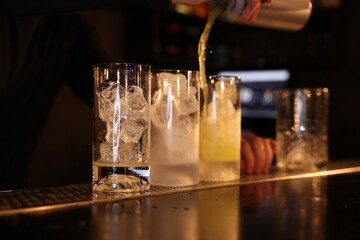 Poster - Bartender pouring energy drink into glass at counter in bar, selective focus