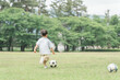 公園の芝生でサッカーをする子ども・男の子（サッカーボール・ドリブル）
