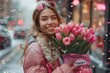A beaming lady adorned in a flowy outfit stands on a bustling street, her delicate features radiating joy as she holds a bunch of vibrant pink tulips, embodying the beauty and grace of nature