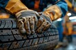 Close-up of a mechanic's hands installing or changing a car tire in a workshop environment.