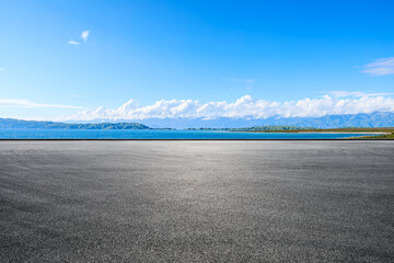 Wall Mural - Asphalt road and blue lake with mountain nature landscape under blue sky