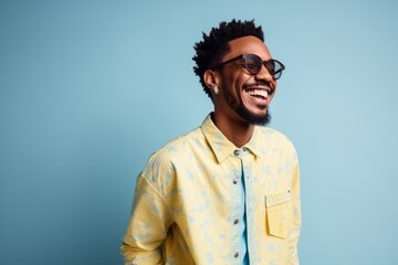 Wall Mural - Portrait of a happy african american man laughing against blue background