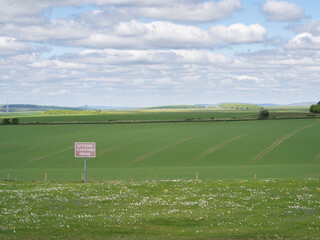 Red sign on open farmland stating out of bounds to unauthorised personnel indicating no public access or right of way