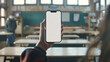 Student teacher hand holding isolated smartphone device in the classroom with blank empty white screen, communication education technology concept