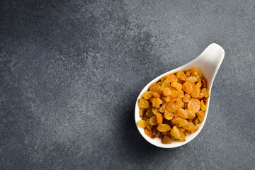 Wall Mural - Close up of dried raisins in a ceramic bowl. On a dark concrete background.