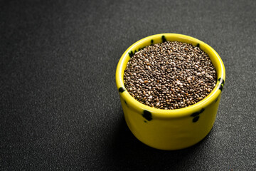 Wall Mural - Close up of chia seeds in a ceramic bowl. Superfood On a dark concrete background.