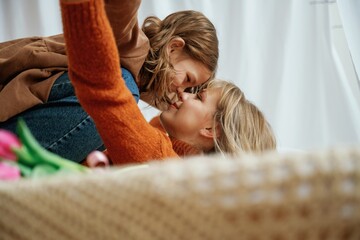 Red flowers on bed, embracing, mother's day. Female parent with daughter is at home