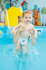 Wall Mural - A little boy is swimming in the pool. Teaching children to swim. Children's swimming school