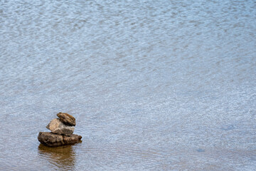 Wall Mural - Stone cairn on striped on the water, three stones tower, simple poise stones, simplicity harmony and balance, rock zen sculptures. Horizontal