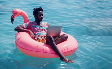 Afro american man sitting and floating in sea at pink inflatable mattress and doing an online freelance job.